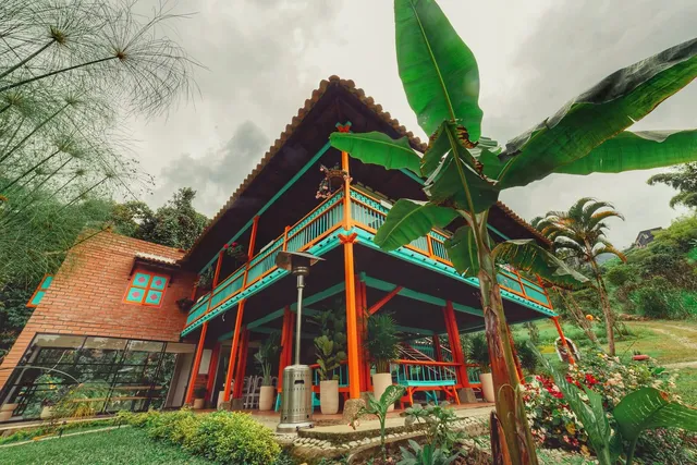 Orange columns and turquoise veranda beside Isla de Pascua’s brick kitchen wing and clay roof.